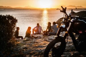 Five motorcycling friends taking a break on coast at sunset, Cagliari, Sardinia, Italy