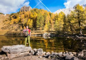 Hiker standing on rock admire the lake and the autumn colors of landscape. Colourful autumn in lake.