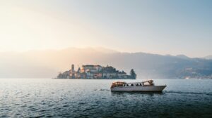 View of the San Giulio island on Lake Orta with tourist boat sailing on the lake at sunset