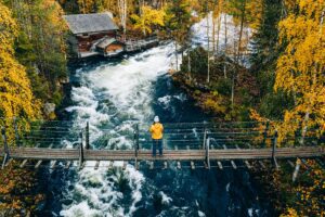 Aerial view of fall forest and blue river with bridge in Finland.