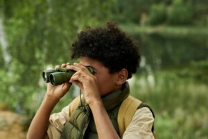 Child using binoculars outdoors in the forest