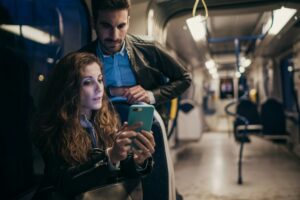 Couple using mobile phone in train, Florence, Italy