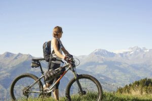 Female mountain biker looking out at mountain landscape, Aosta Valley, Aosta, Italy