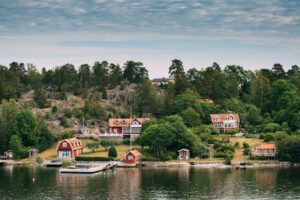 Sweden. Beautiful Red Swedish Wooden Log Cabin House On Rocky Is