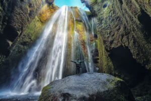 Traveler stunned by Gljufrabui waterfall cascade in Iceland.