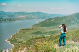 Young woman standing against blue sea and mountains background East Kazakhstan