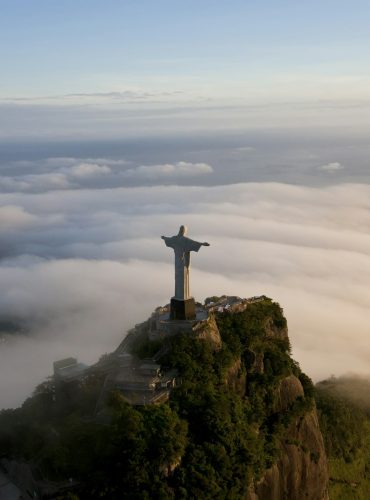 High angle view of colossal Christ Redeemer statue surrounded by clouds, Corcovado, Rio de Janeiro,